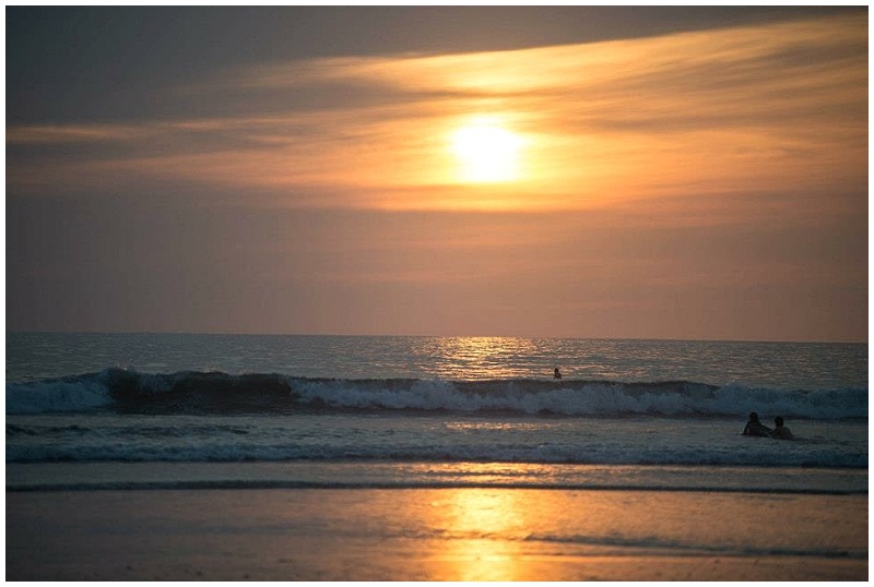 Surfers in the ocean at sunset in Nosara, Costa Rica