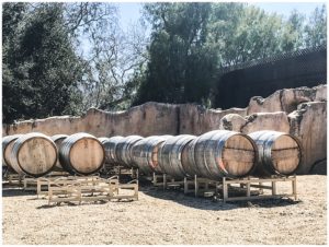 Wine barrels lines up along a stone wall at Sunstone Winery